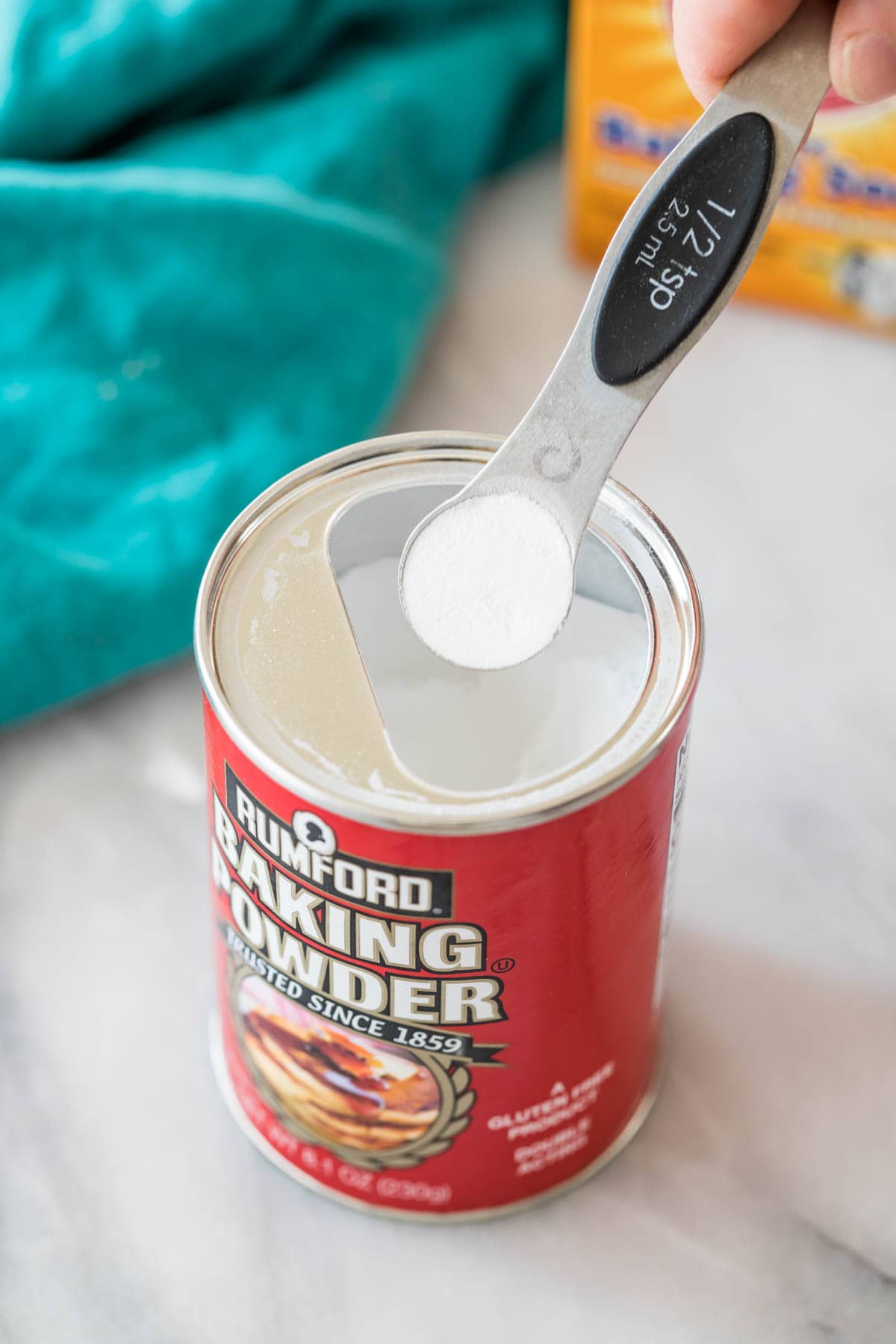 measuring spoon scooping baking powder out of its container