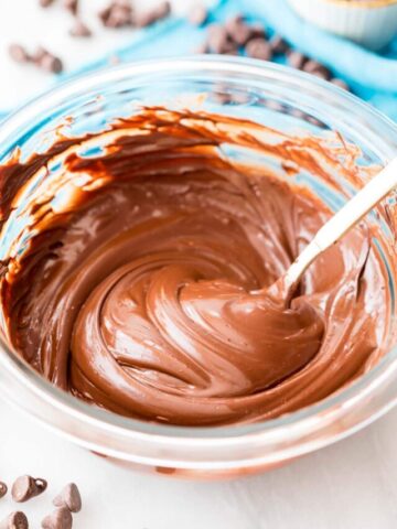 melted chocolate in a clear bowl being stirred by a spoon