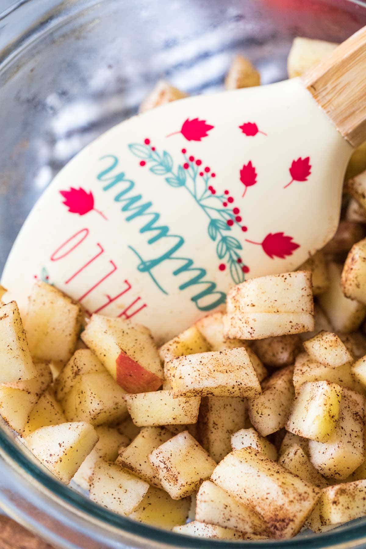 spatula stirring chopped apples coated in cinnamon