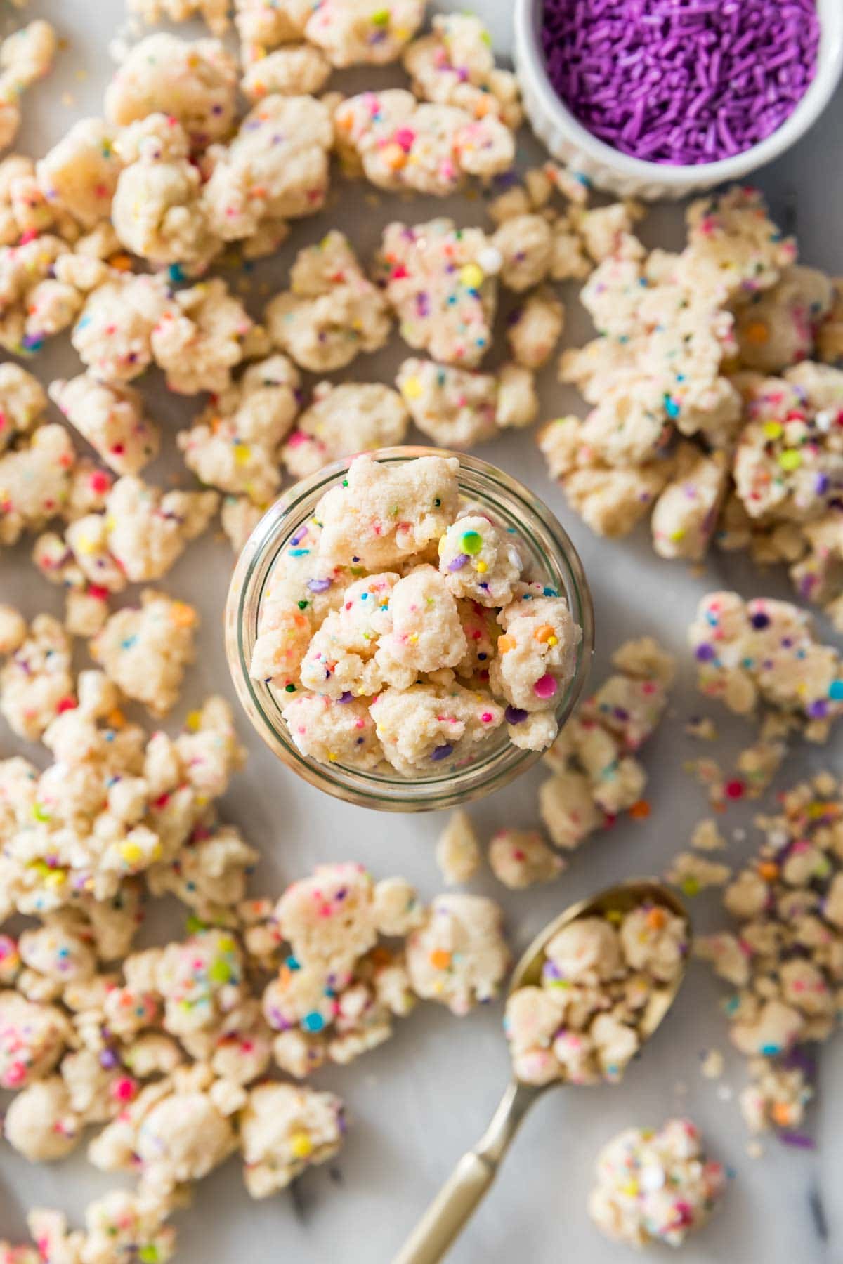 overhead view of a glass jar of funfetti cake crumbs surrounded by more crumbs