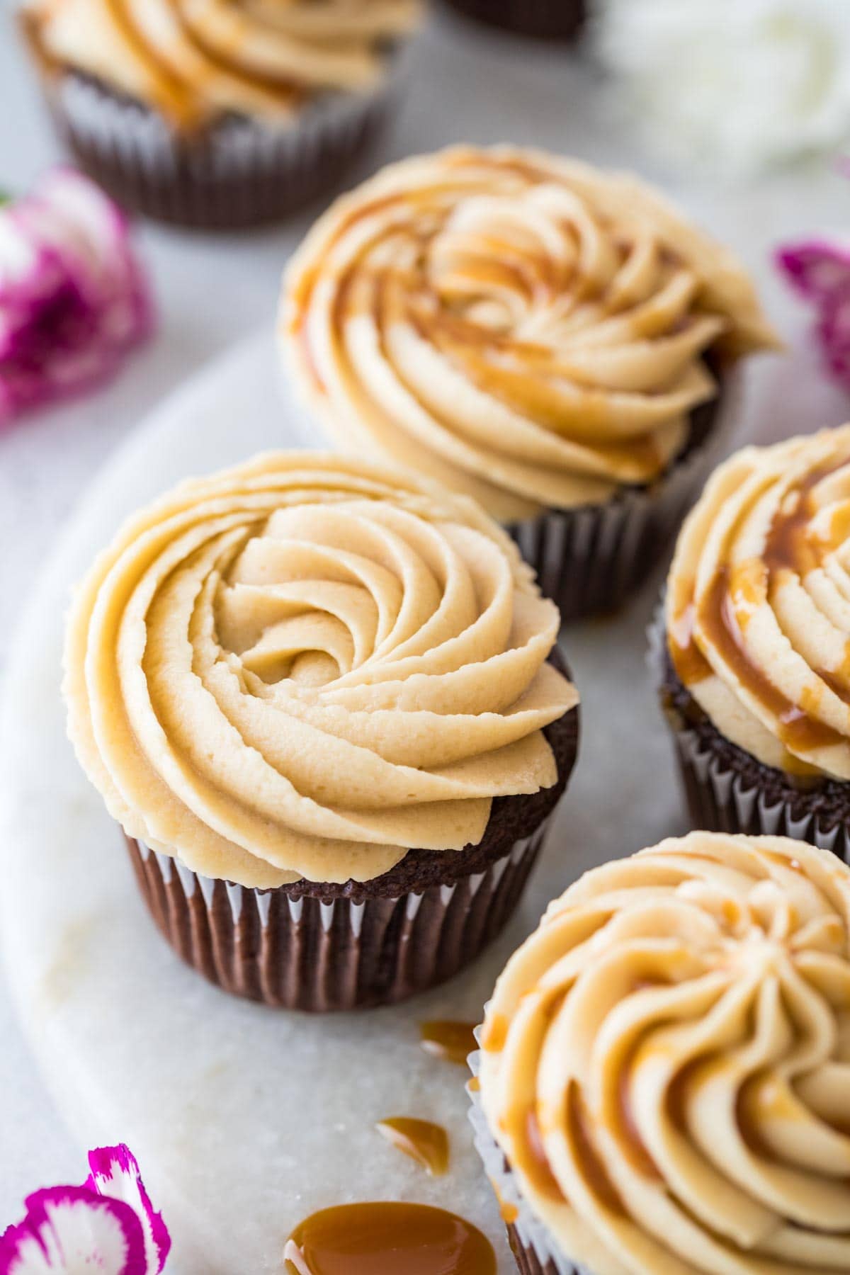 overhead view of cupcakes topped with piped frosting and a drizzle of caramel sauce