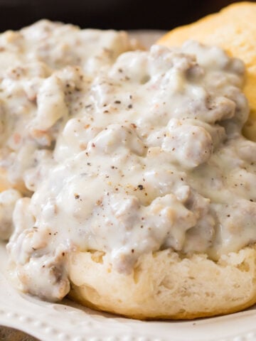 Sausage gravy recipe poured over open faced biscuits