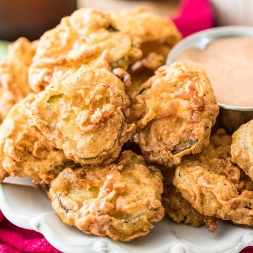 Homemade fried pickles stacked around a dipping sauce.
