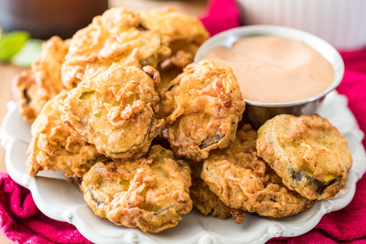 Homemade fried pickles stacked around a dipping sauce.