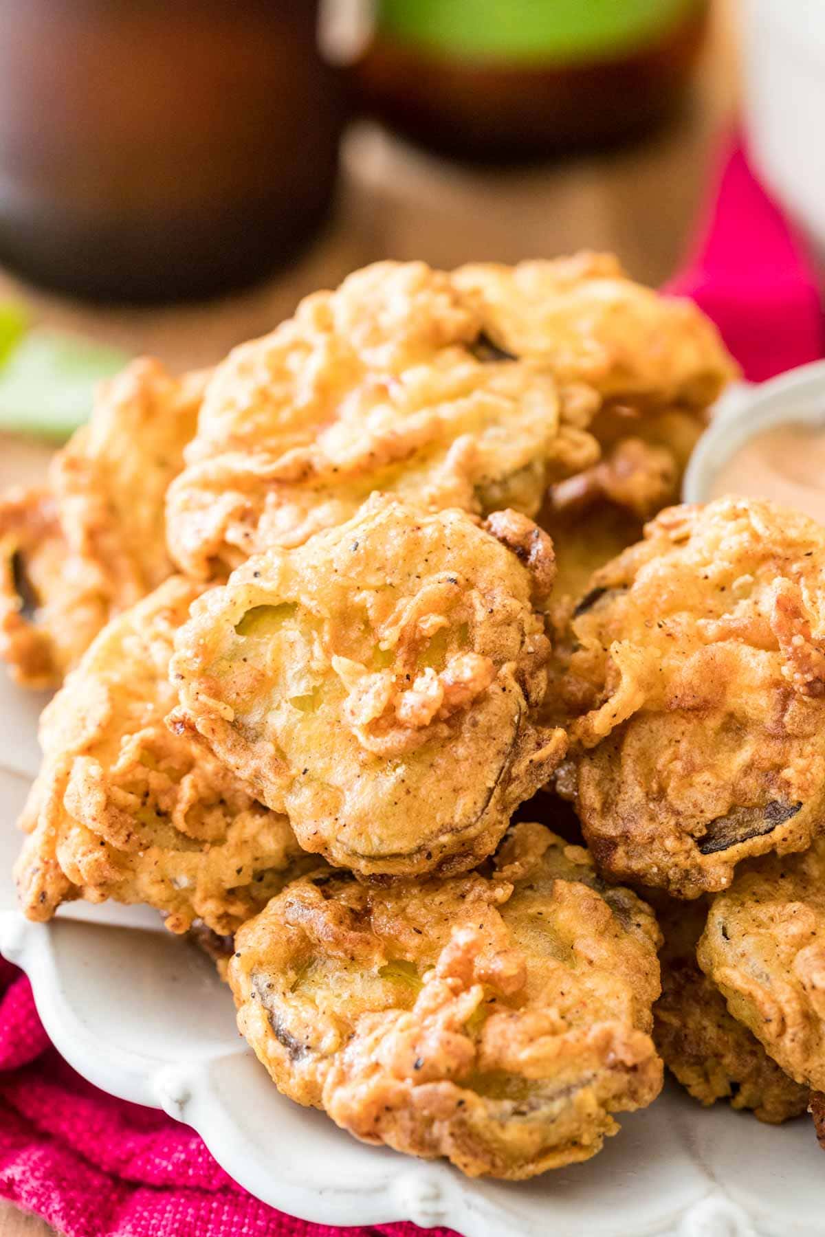 Breaded and fried pickle slices stacked on a plate.