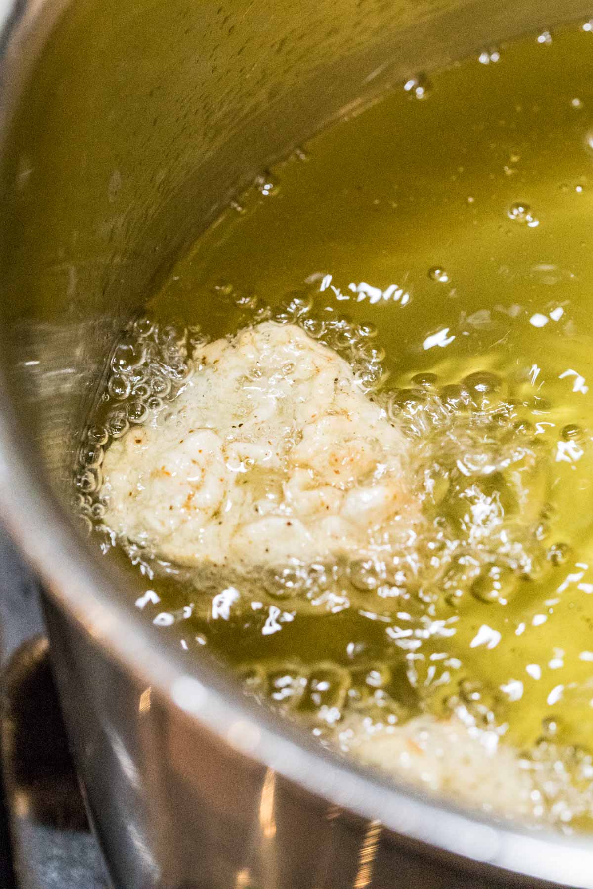 Breaded pickle slice frying in oil.
