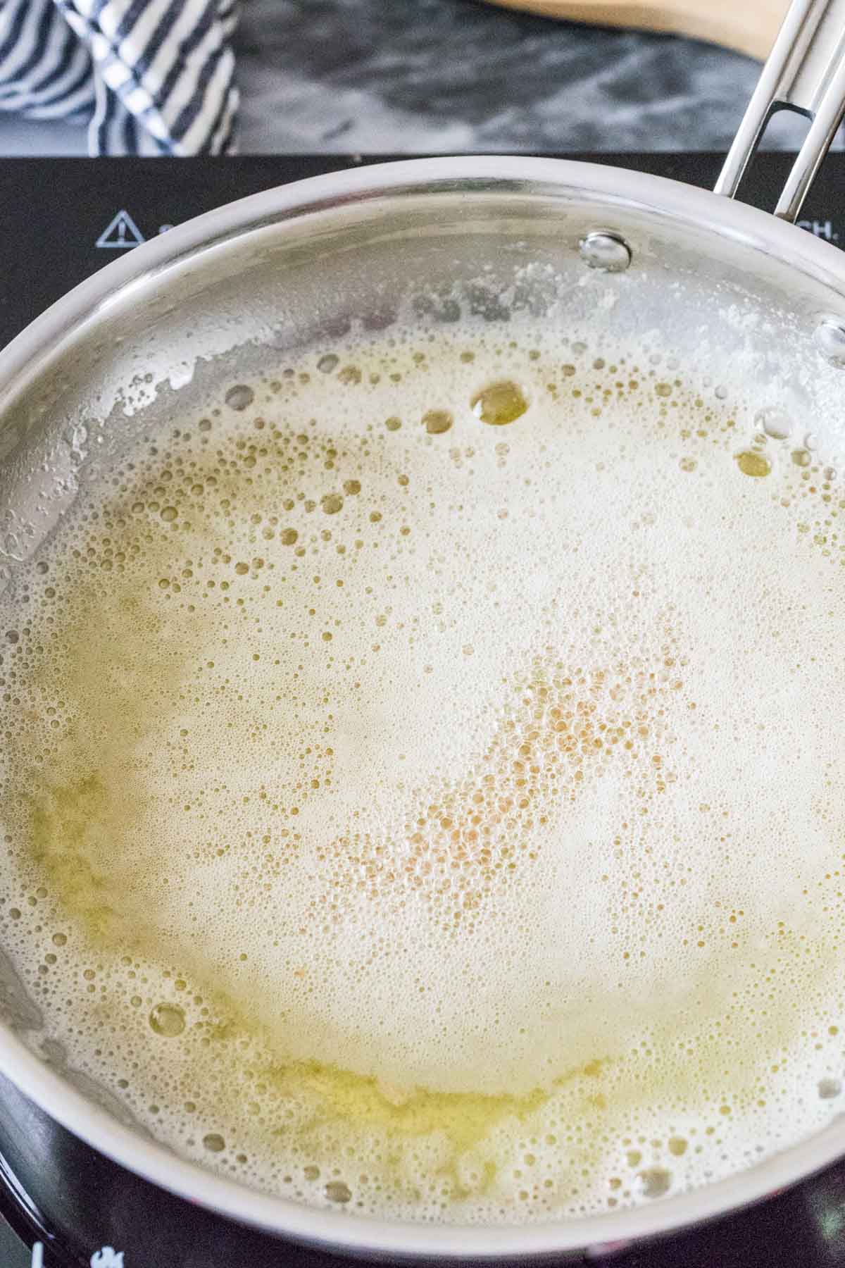 melted butter that is foaming and bubbling on the stovetop