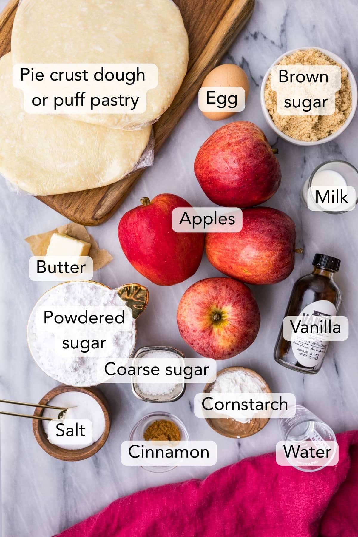 overhead view of ingredients for an apple turnover recipe including pastry dough, apples, cinnamon and more.