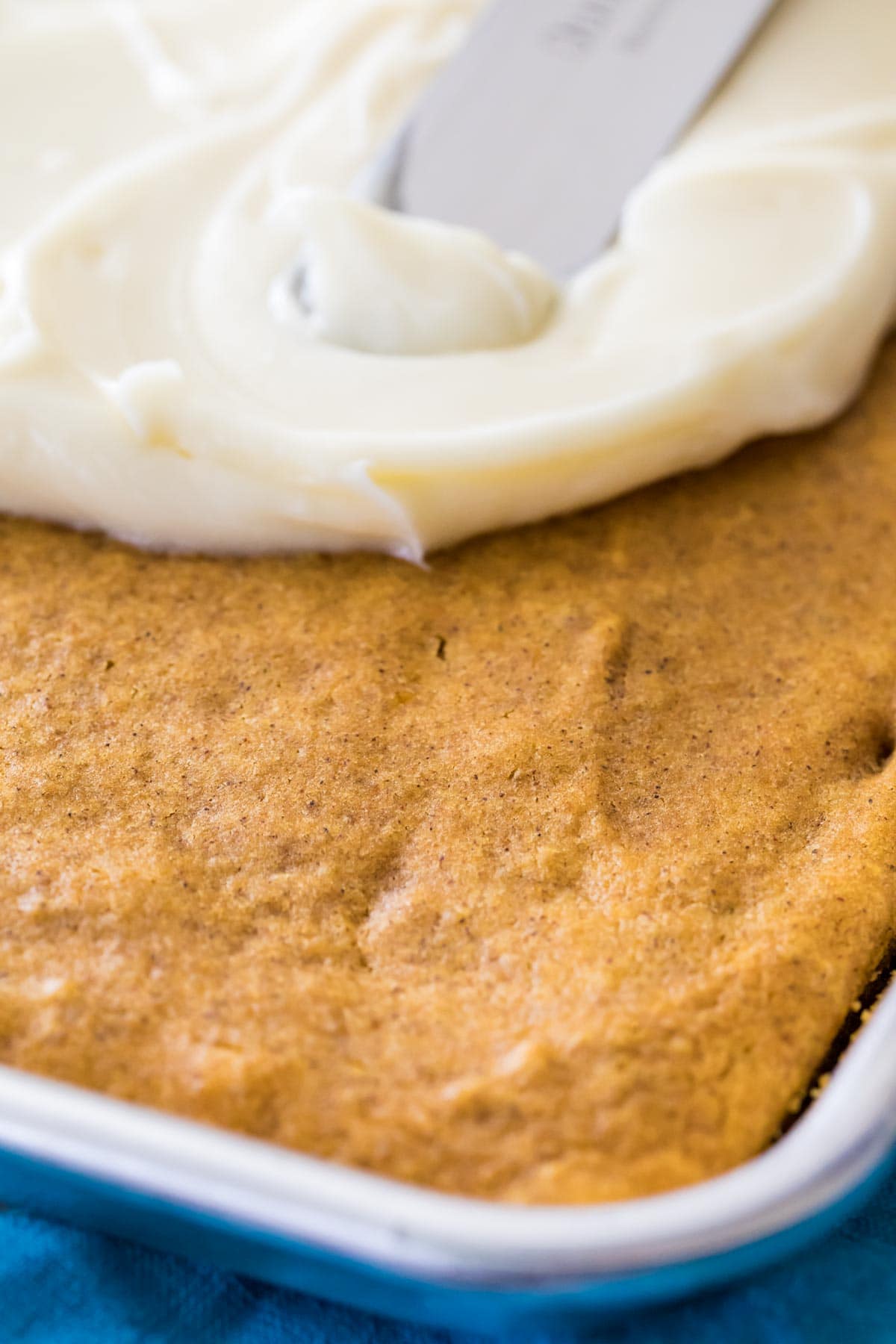 Cream cheese frosting being spread over bars.