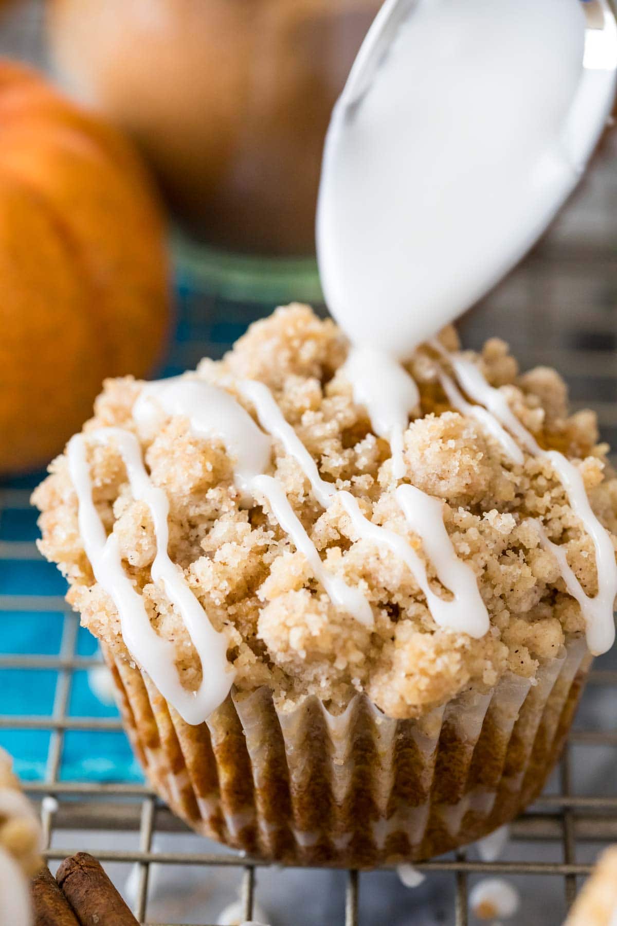 vanilla glaze being drizzles onto a streusel topped muffin