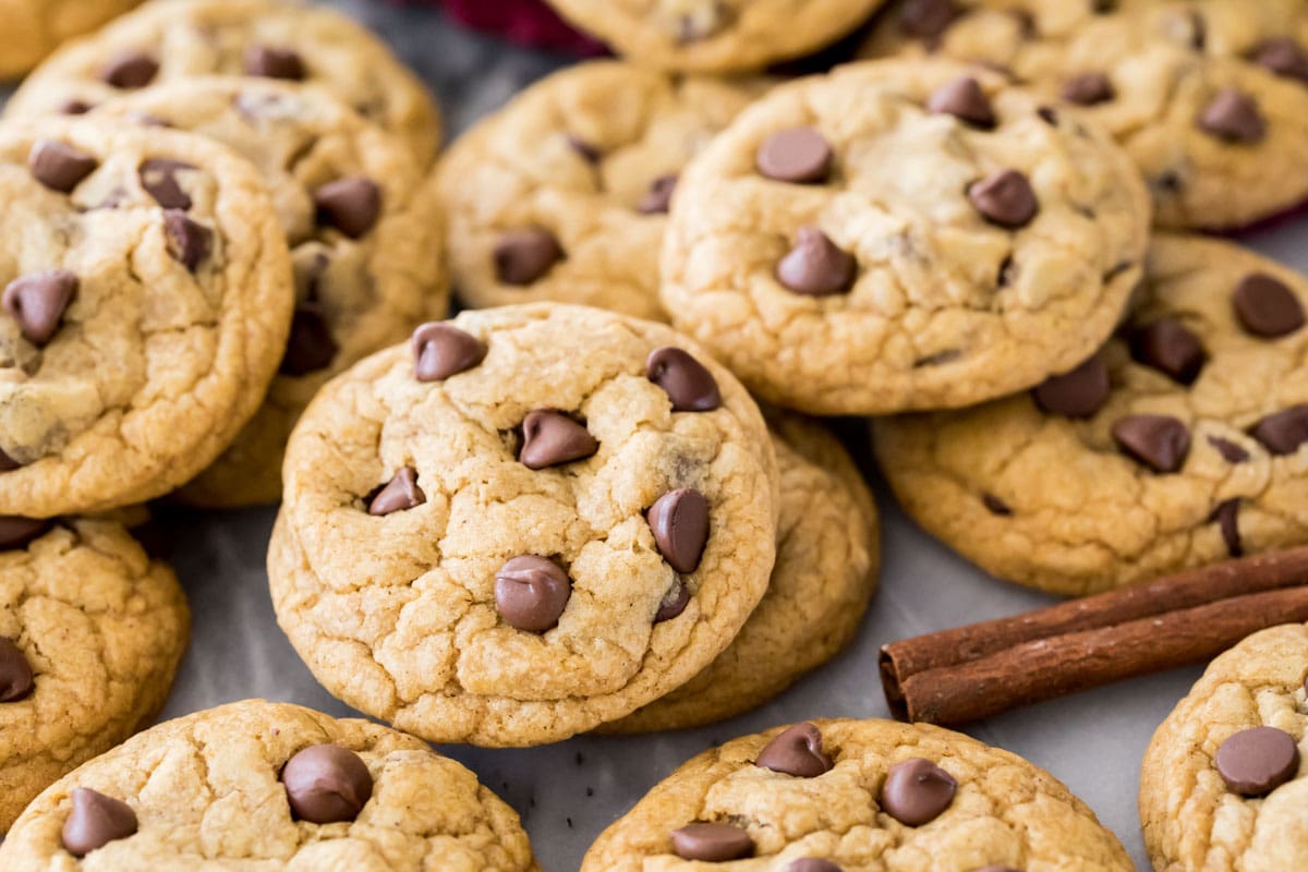 Pile of chocolate chip cookies next to a cinnamon stick.