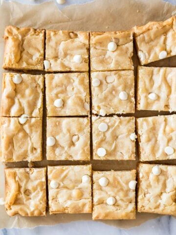 Overhead view of a batch of white chocolate brownies cut into 16 pieces.