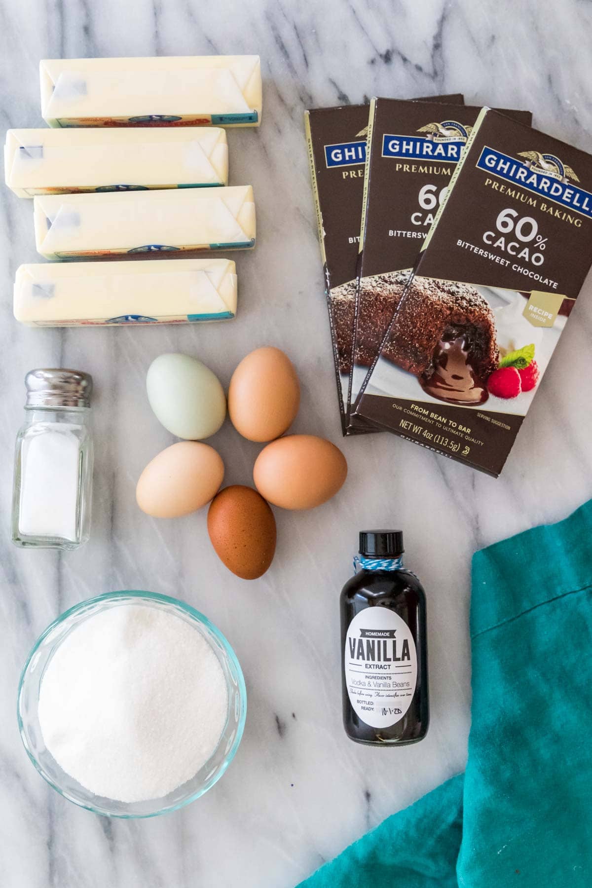 overhead view of ingredients including butter, chocolate bars, eggs, vanilla, salt, and sugar