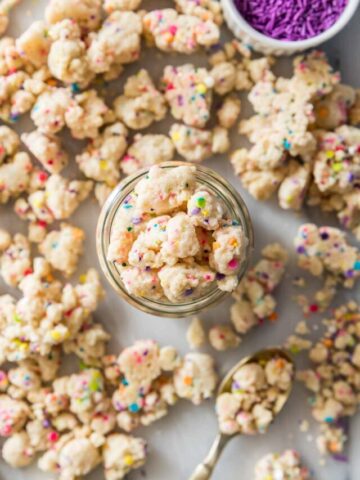 overhead view of a glass jar of funfetti cake crumbs surrounded by more crumbs