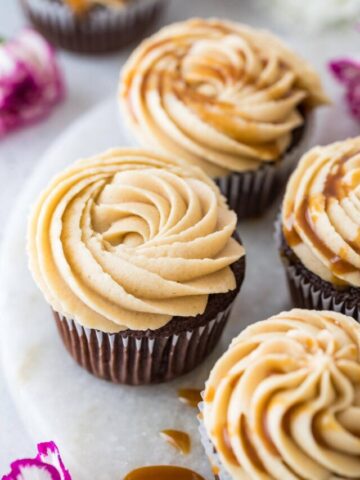 overhead view of cupcakes topped with piped frosting and a drizzle of caramel sauce