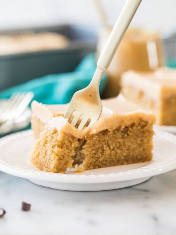 Fork taking a bite of a slice of sheet cake.