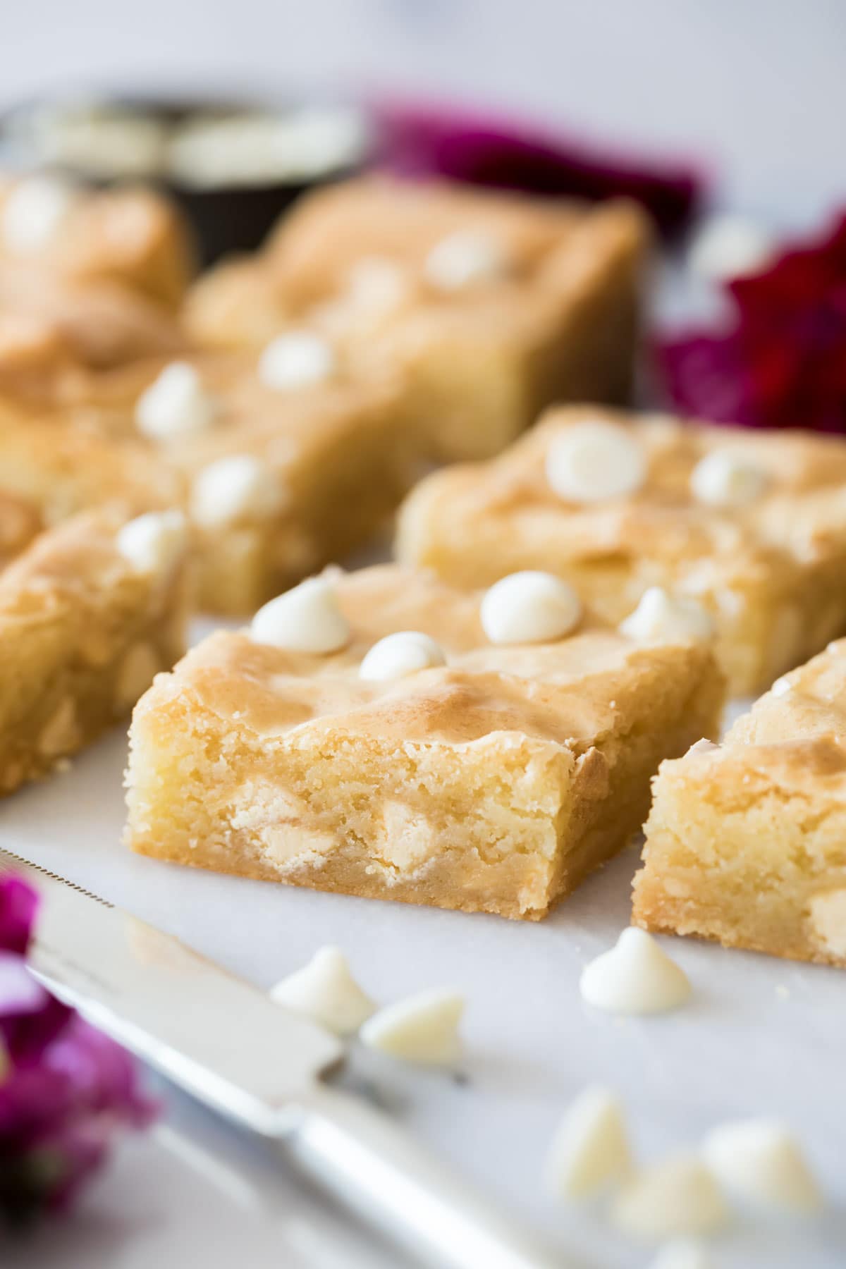 Close-up view of neatly-cut, caramel-colored brownies studded with white chocolate chips.