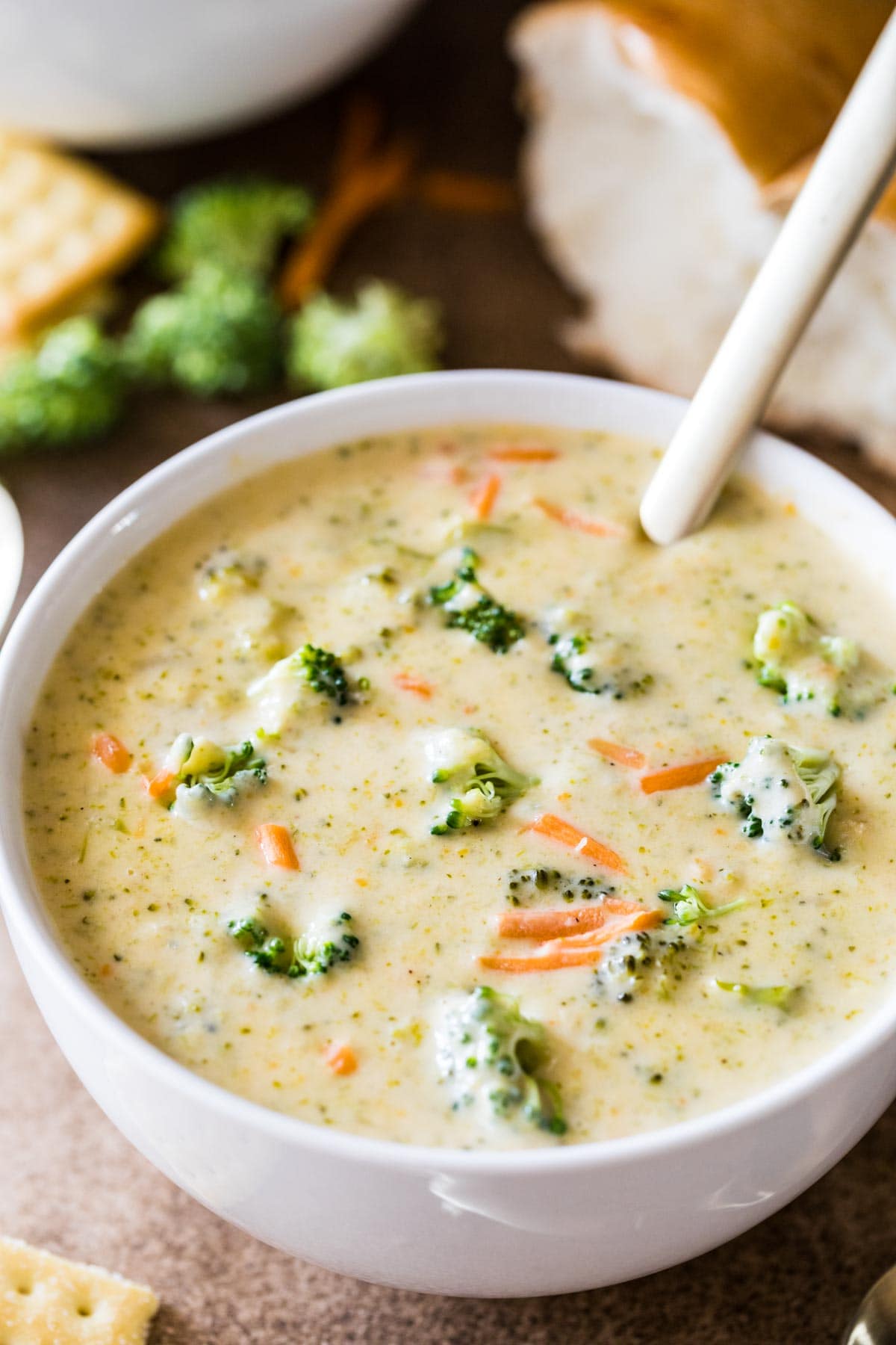 Bowl of soup topped with broccoli bits and shredded carrots.