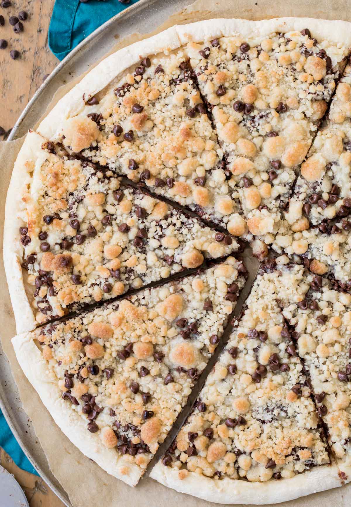 Overhead view of a chocolate chip dessert pizza that's been cut into slices.