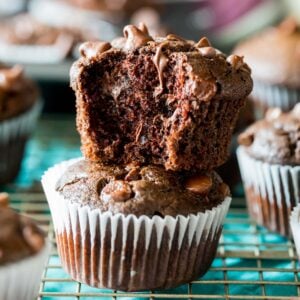 Two double chocolate muffins stacked on top of each other with the top muffin missing a bite.