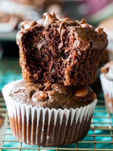 Two double chocolate muffins stacked on top of each other with the top muffin missing a bite.