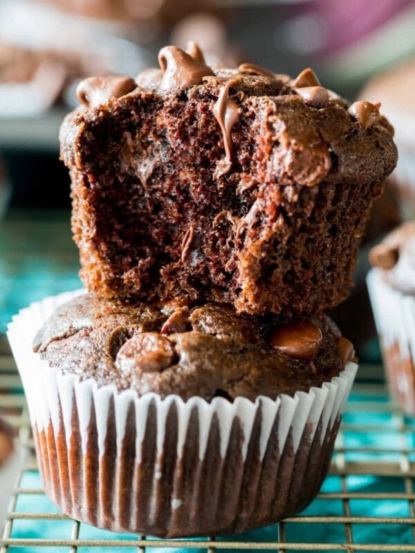 Two double chocolate muffins stacked on top of each other with the top muffin missing a bite.