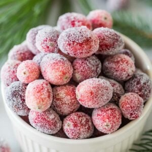 Overhead view of sugared cranberries in a white bowl.
