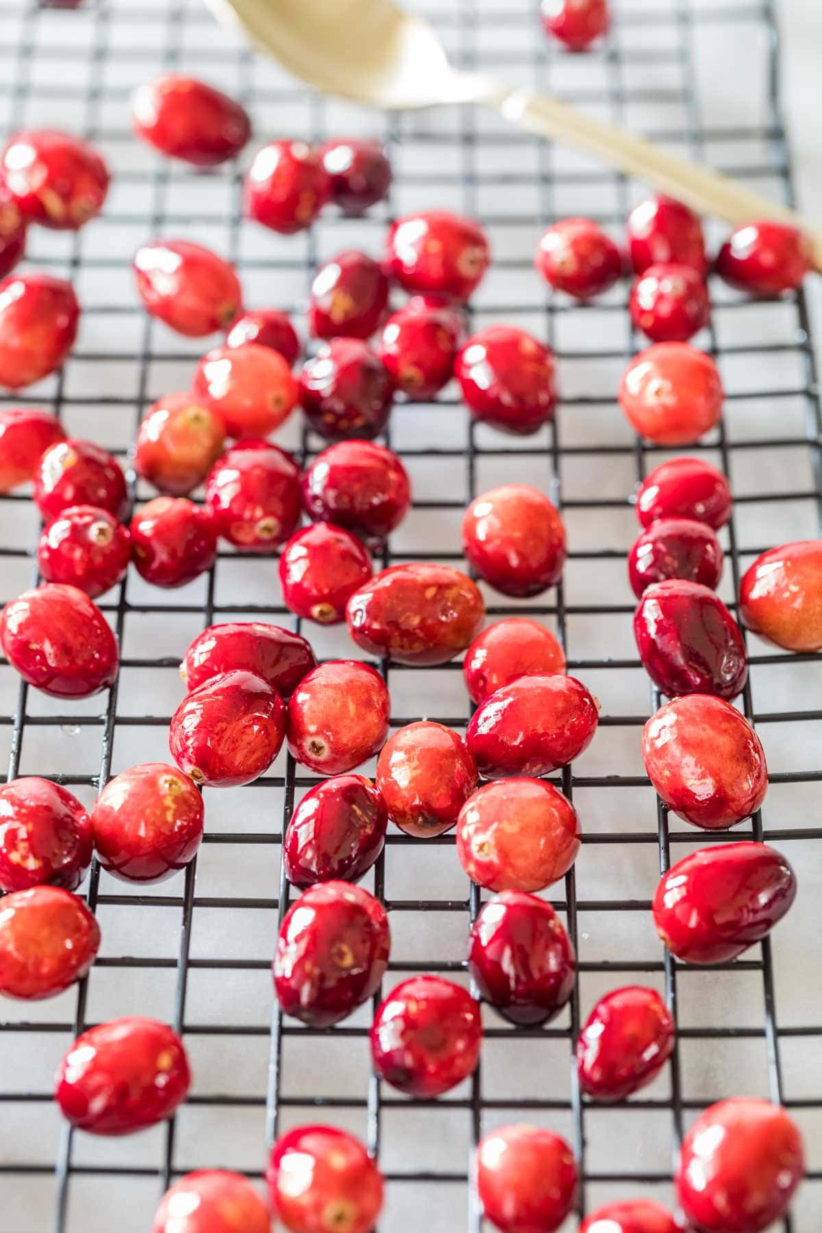 Candied cranberries on a cooling rack after being dipped in simple syrup.