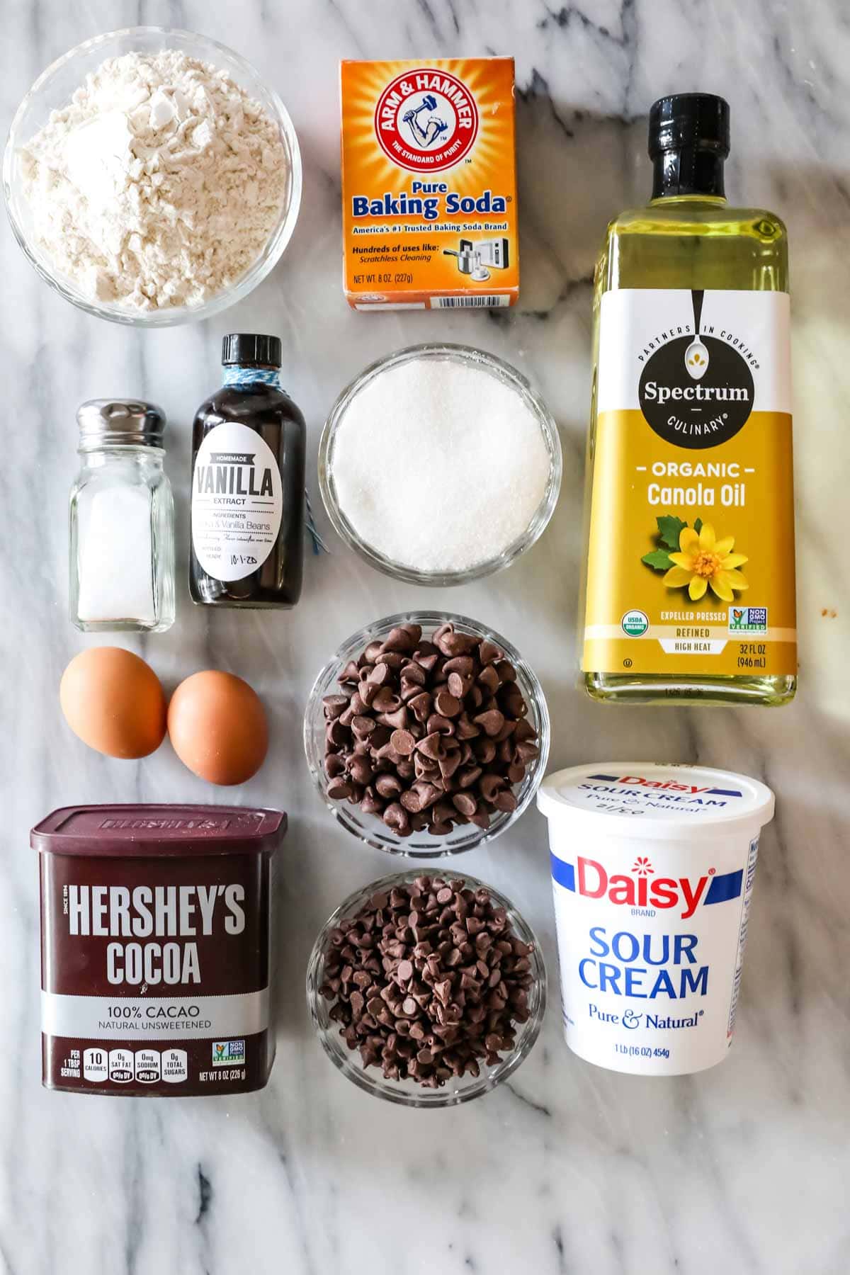 Overhead view of ingredients including cocoa powder, chocolate chips, oil, sour cream, and more.