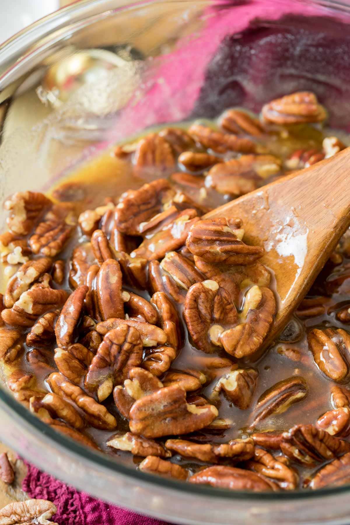 Spoon stirring pecans into a syrup for pie.