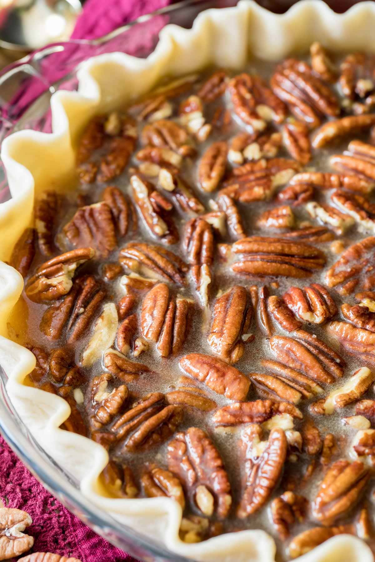 Pecans in a syrupy filling poured into a pie crust before baking.