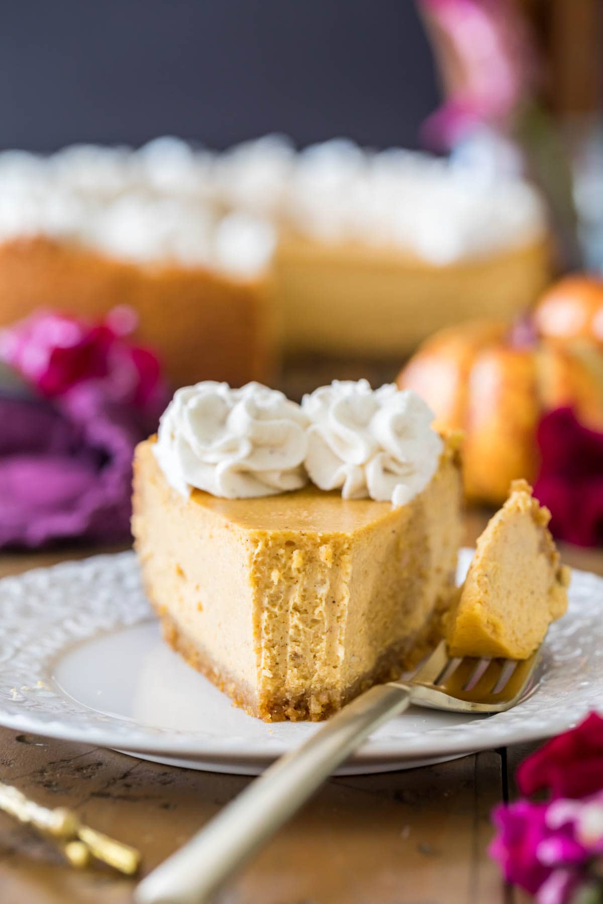 Head-on view of a slice of cheesecake after the first forkful has been taken.