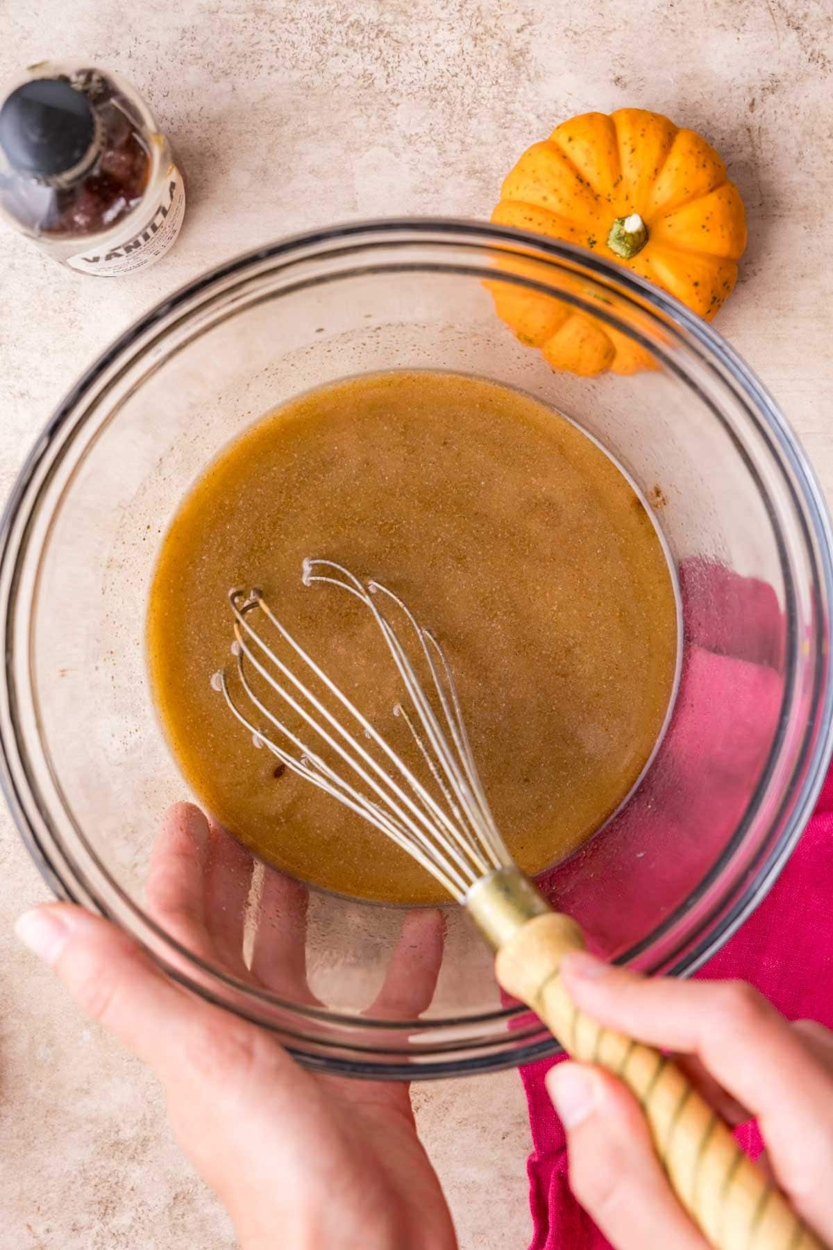 Whisking pumpkin spice into melted butter in a glass bowl.