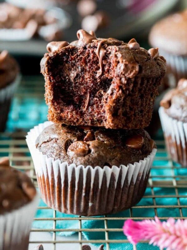 Two double chocolate muffins stacked on top of each other with the top muffin missing a bite.