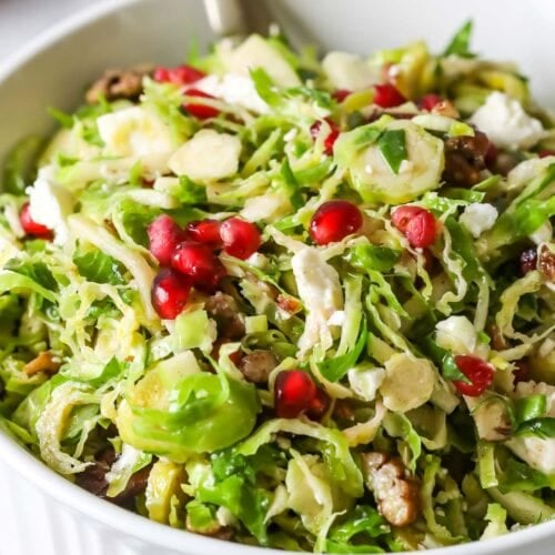 Close-up shot of a shaved brussels sprouts salad topped with pomegranate arils.