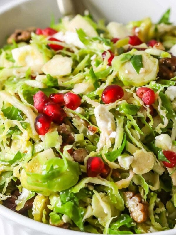 Close-up shot of a shaved brussels sprouts salad topped with pomegranate arils.