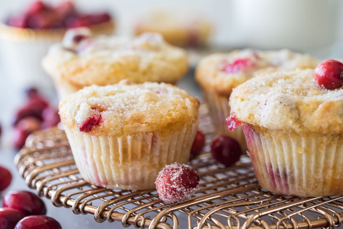 Muffins on a metal cooling rack surrounded by sugared cranberries.