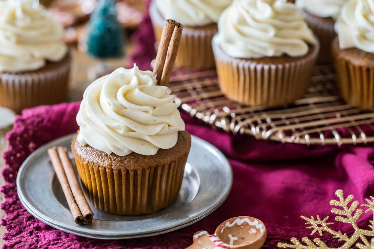 Cupcakes topped with a spiced cream cheese frosting and garnished with cinnamon sticks.