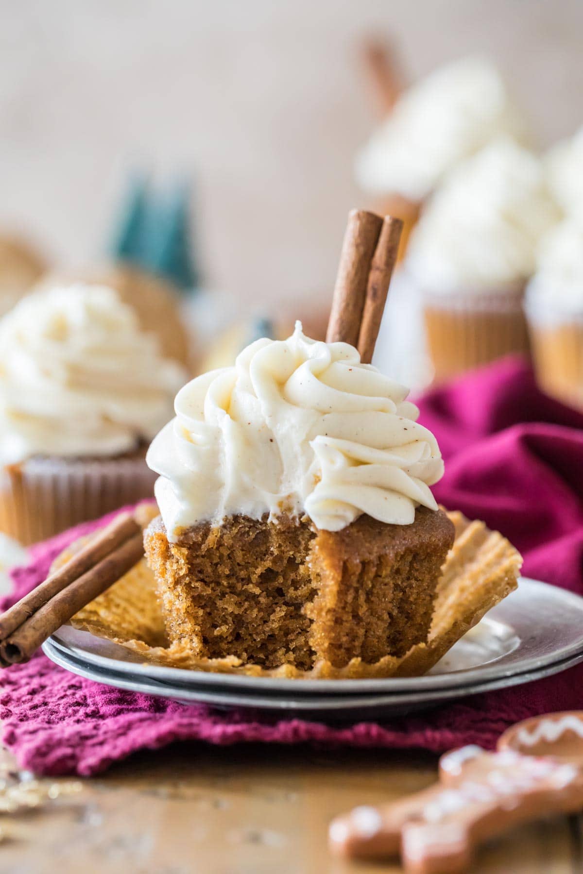 Unwrapped cupcake with piped frosting and a cinnamon stick garnish with one bite missing.