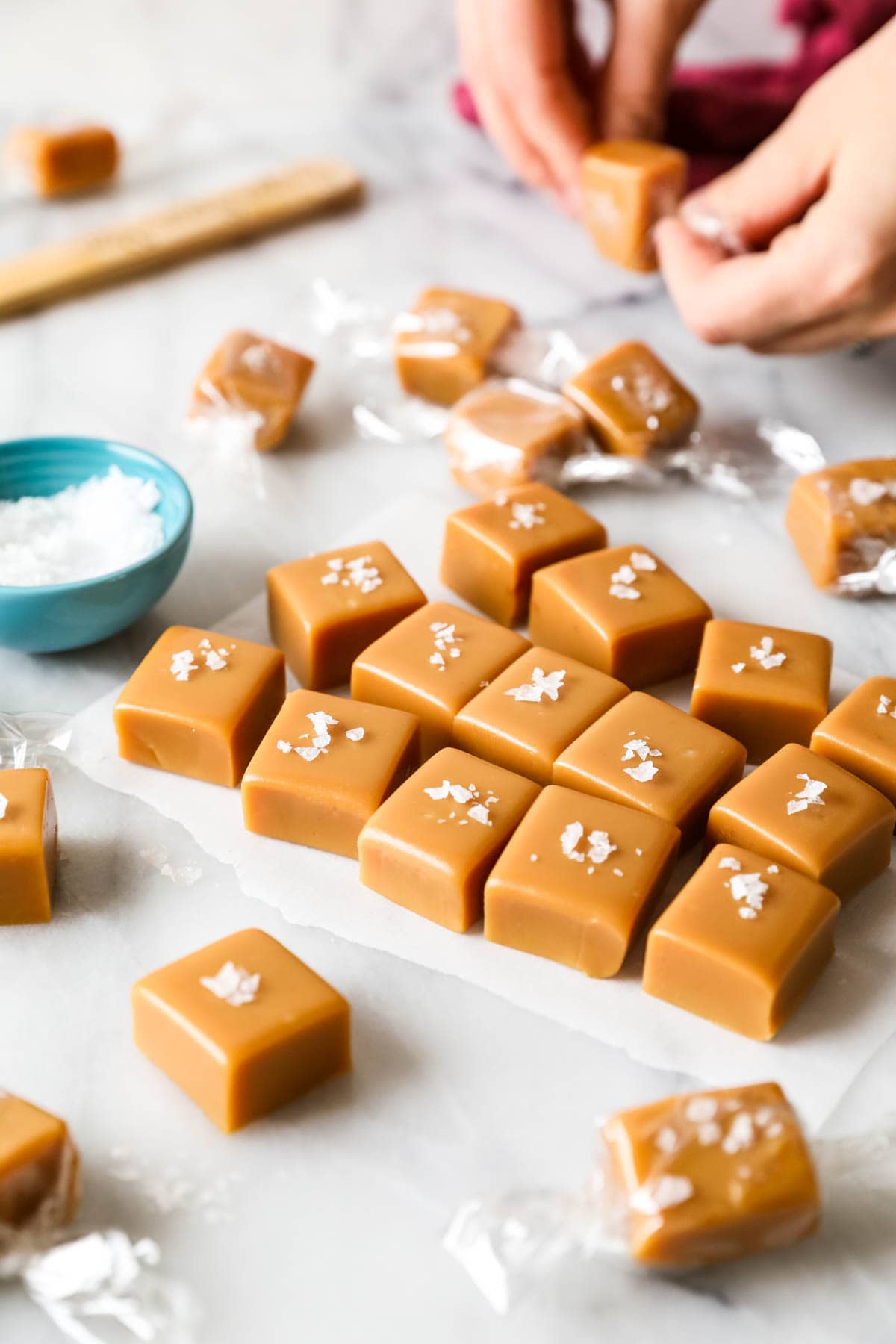 Square-cut caramels being wrapped in cellophane.