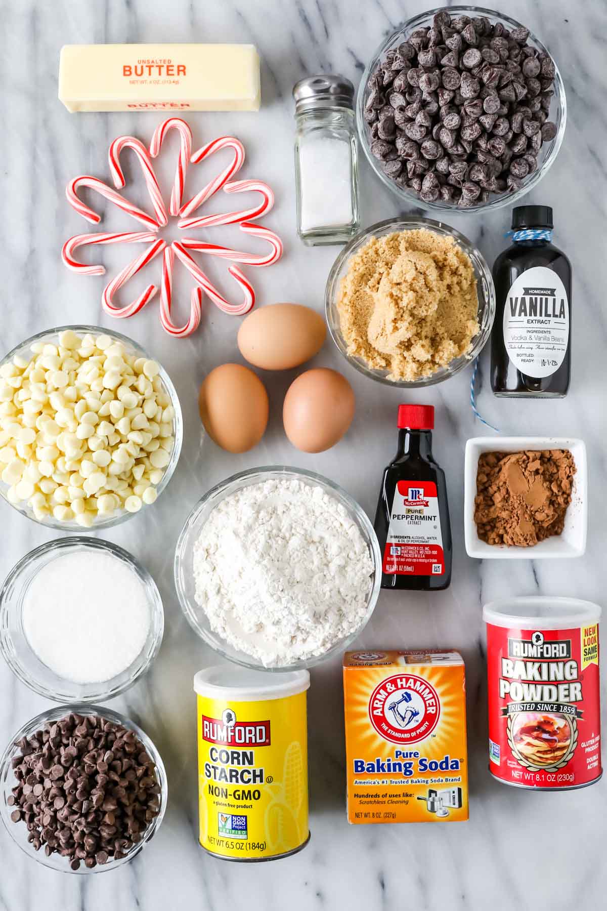 Overhead view of ingredients including candy canes, white chocolate chips, cocoa powder, and more.