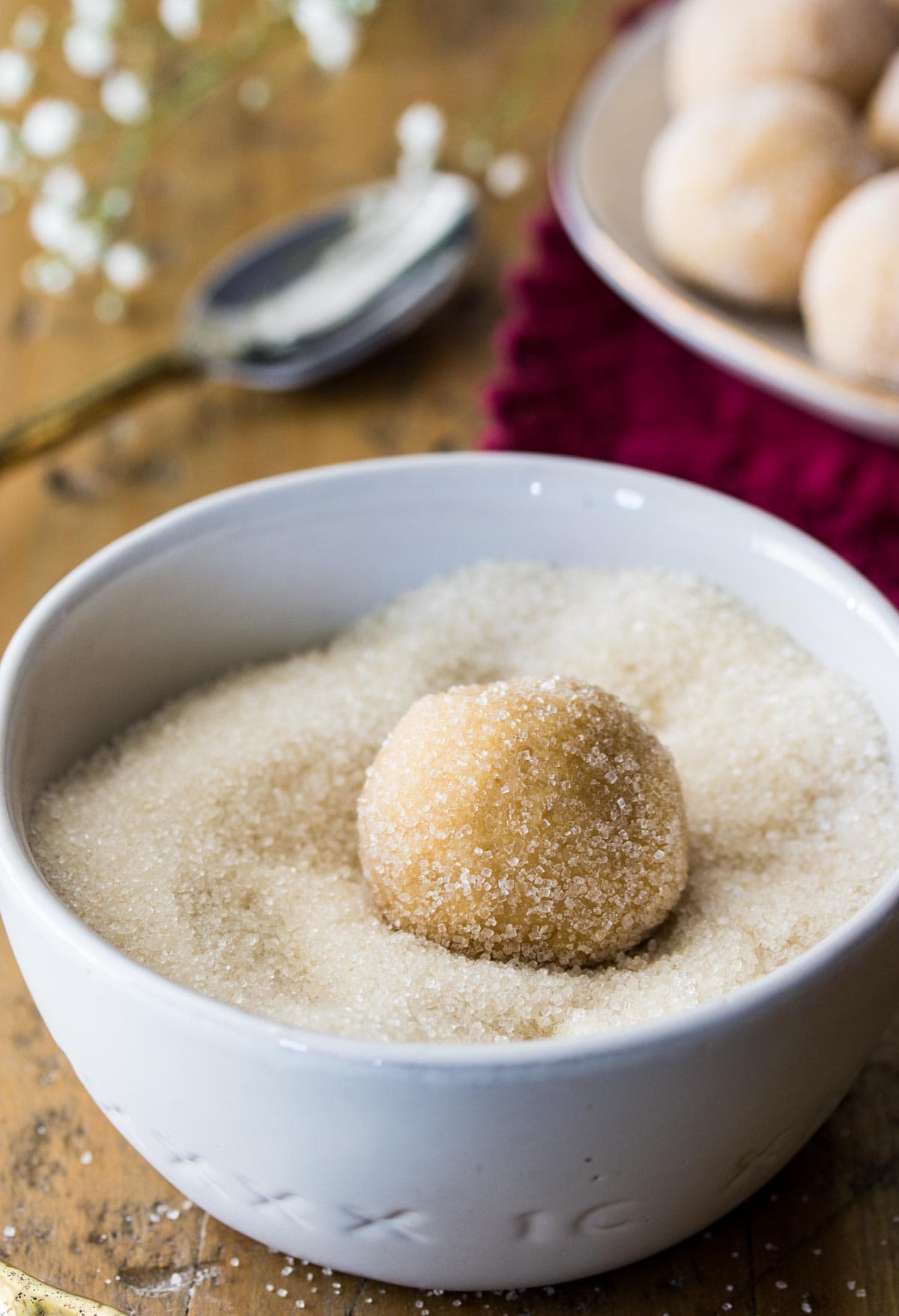 Peanut butter cookie dough ball being rolled through sugar.