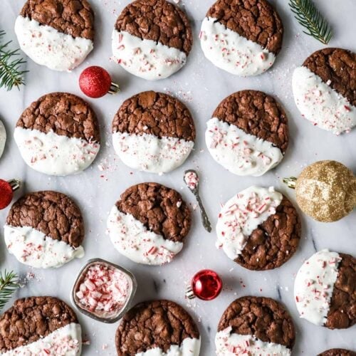 Overhead view of chocolate peppermint bark cookies that have been half dipped in white chocolate and sprinkled with crushed candy canes.
