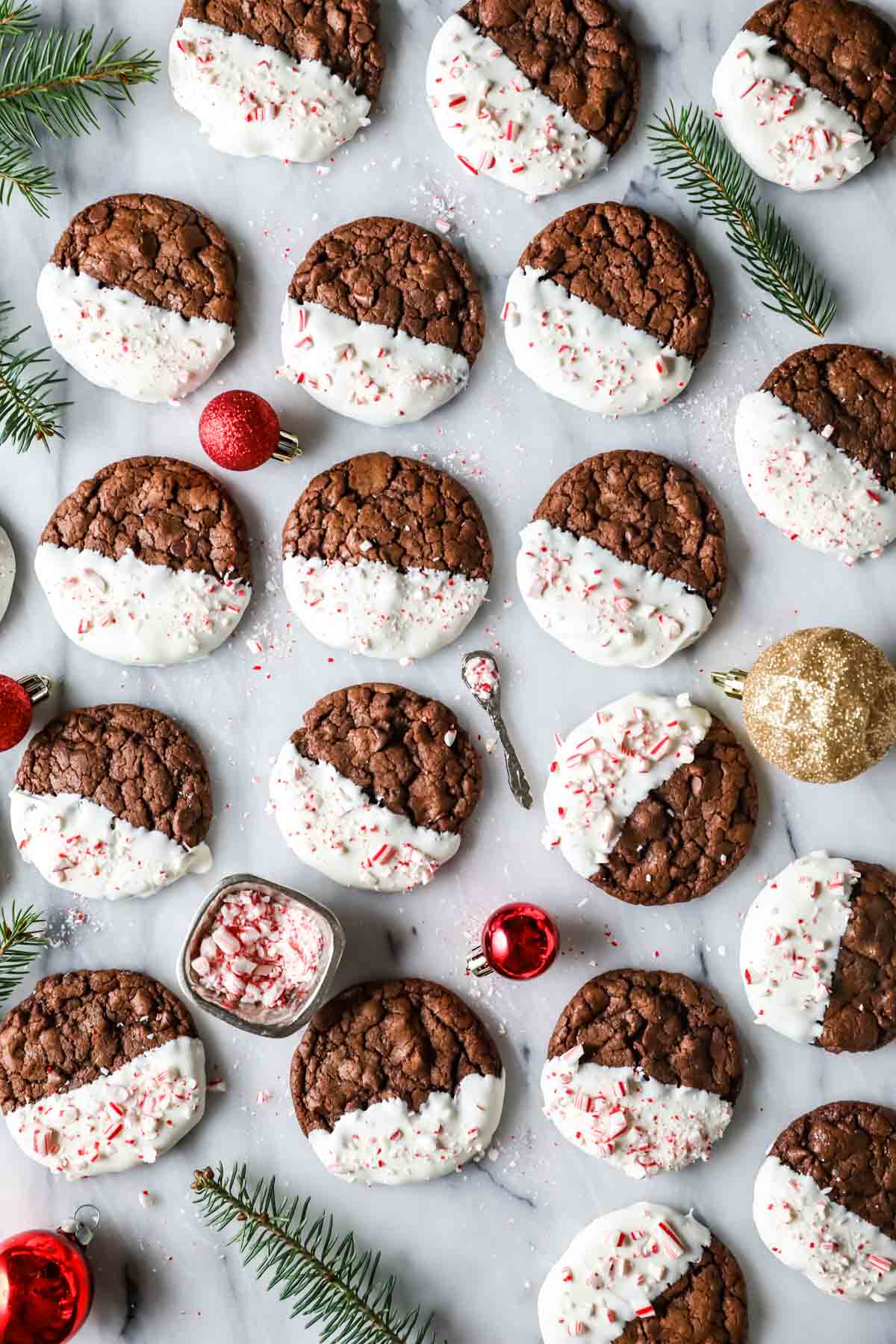 Overhead view of chocolate peppermint bark cookies that have been half dipped in white chocolate and sprinkled with crushed candy canes.