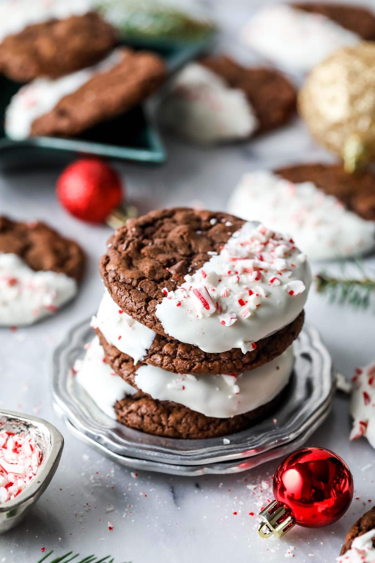 Stack of chocolate cookies half dipped in white chocolate and sprinkled with candy canes.