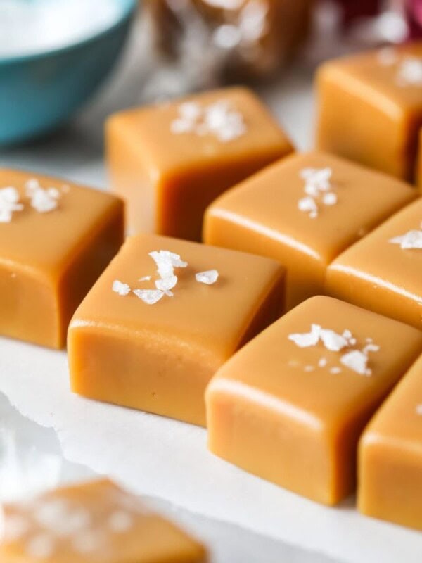 Close up view of squares of homemade caramel topped with flaky sea salt.