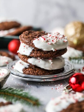 Stack of chocolate cookies half dipped in white chocolate and sprinkled with candy canes.