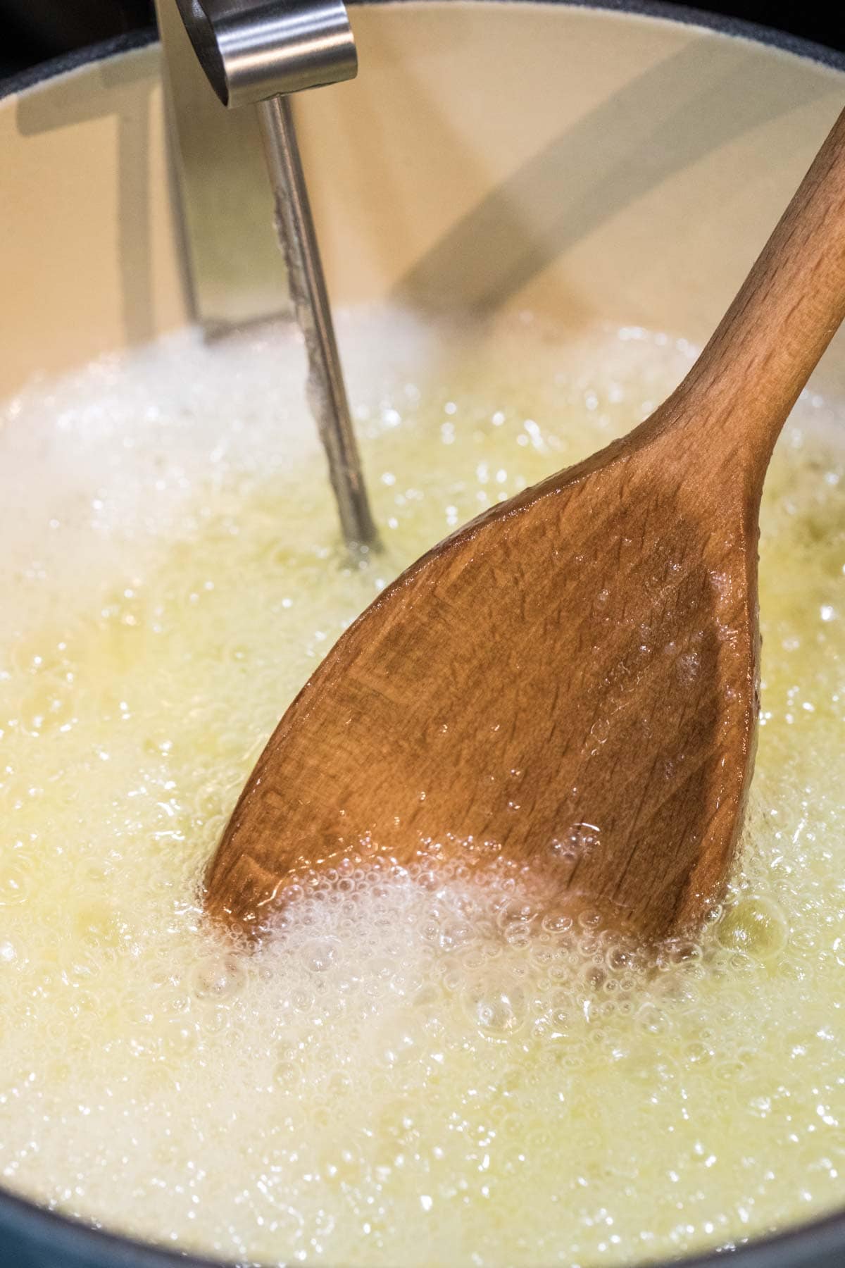 Spoon stirring a candy mixture that's bubbling.