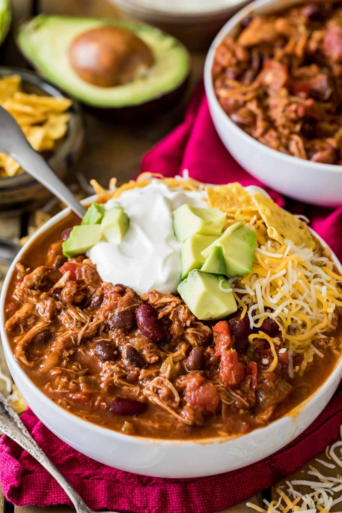 Bowl of turkey chili topped with sour cream, avocado, and shredded cheese.