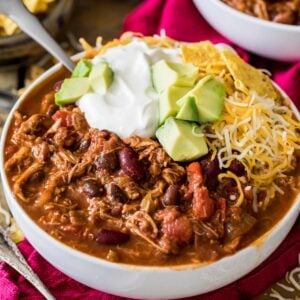Bowl of turkey chili topped with sour cream, avocado, and shredded cheese.